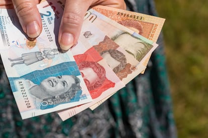 A woman is holding Colombian pesos in her hand.  Hands on the background of the dress. Economic crisis