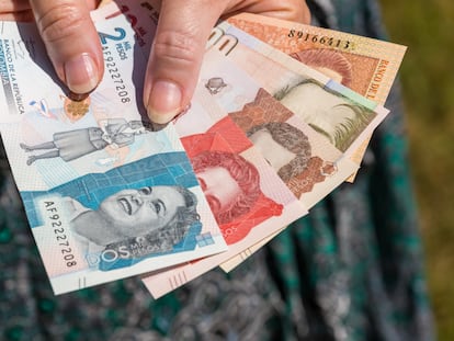 Una mujer sostiene pesos colombianos.