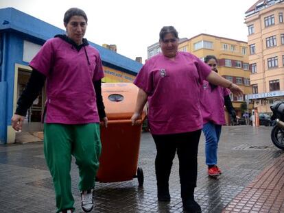 Las voluntarias empujan por las calles de A Coruña uno de los contenedores con los que recogen el aceite usado.