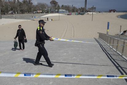 Un agente de la Guardia Urbana de Barcelona cierra el acceso a una playa, el 15 de marzo.