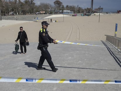 Un agente de la Guardia Urbana de Barcelona cierra un acceso en la playa.