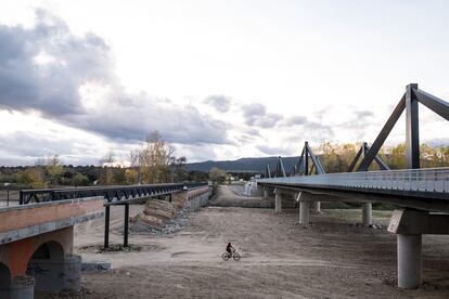 Una persona cruza por el río seco de Aldea del Fresno donde circuló la dana y cuyo puente quedó arrasado.