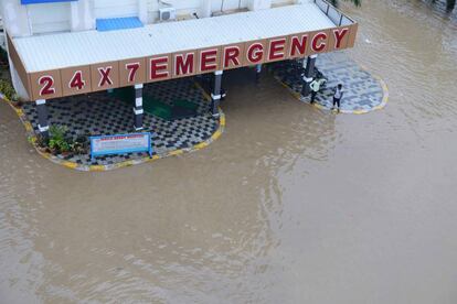 Ciudadanos esperan a las puertas de un hospital privado rodeado de agua debido a las fuertes lluvias, en Suraram, a las afueras de Hyderabad (India).