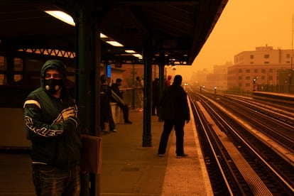 A man waits for the subway while wearing a facemask as smoke haze from wildfires in Canada blankets a neighborhood in the Bronx borough of New York City, on June 7, 2023.