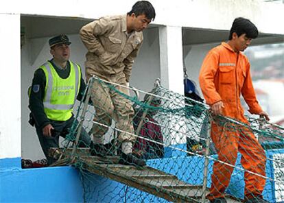 Un guardia civil acompaña a dos tripulantes del congelador <i>Wisteria</i> para tomarles declaración.