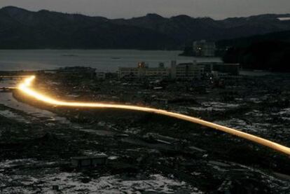 El tráfico de vehículos ilumina una carretera que atraviesa la devastada ciudad de Minamisanriku, en la prefectura de Miyagi.