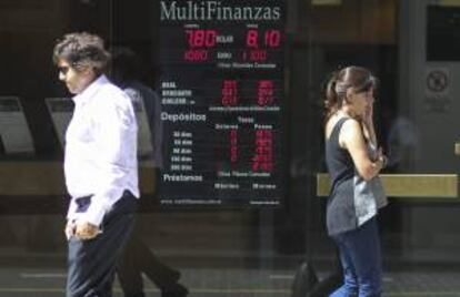 Dos personas caminan frente a una casa de cambios  en Buenos Aires (Argentina).