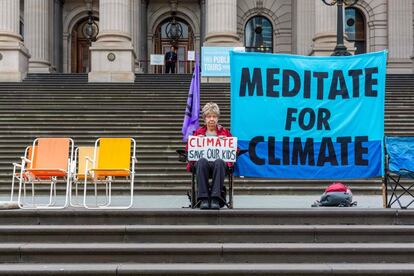Una manifestante sostiene un cartel contra el cambio climatico frente a la Casa del Parlamento, en Melborune (Australia).