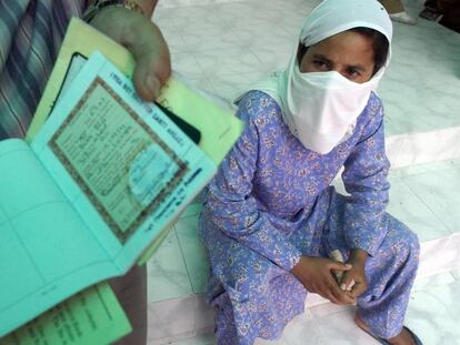 Una mujer observa el pasaporte y otros documentos oficiales en manos de un pariente en la ciudad de Nueva Delhi, en 2003.