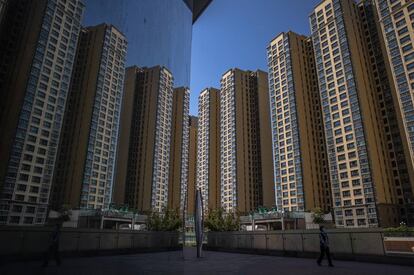 Una mujer camina en una plaza de la ciudad, junto a sus edificios de apartamentos construidos por Evergrande / EFE (ROMAN PILIPEY)