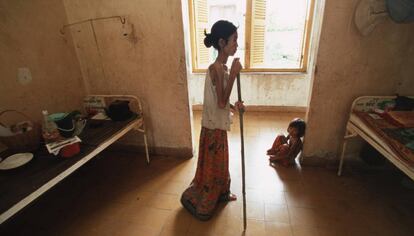 Una mujer con VIH usa un bastón para caminar hacia su cama de un hospital de Camboya.