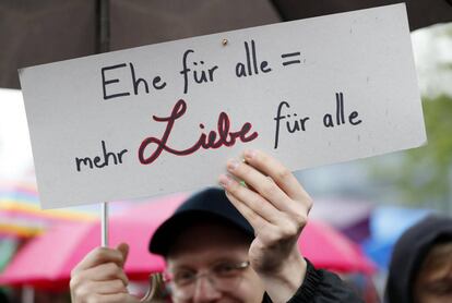 Un hombre sostiene una pancarta en la que se puede leer 'Matrimonio para todos: más amor para todos' mientras varias personas celebran la aprobación de la legalización del matrimonio homosexual en el Parlamento ante la Cancillería en Berlín (Alemania), 30 de junio de 2017.