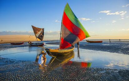 Una turista haciendo una foto a una &#039;jangada&#039;, tradicional barca pesquera multicolor de vela triangular, en Jericoacoara (Brasil).