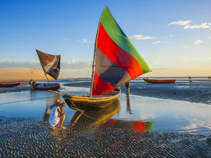 Una turista haciendo una foto a una &#039;jangada&#039;, tradicional barca pesquera multicolor de vela triangular, en Jericoacoara (Brasil).
