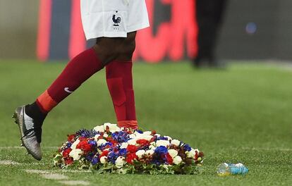 Un jugador de Francia camina junto a unas corona de flores después del  partido amistoso entre Inglaterra y Francia en el estadio de Wembley.  