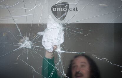 Una hombre limpia la puerta de entrada de la sede de Unió rota en la madrugada después de las elecciones.