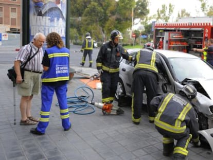 Los bomberos, durante la excarcelaci&oacute;n de una ocupante de uno de los coches. 