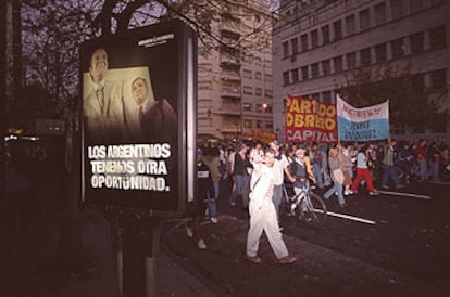 Una manifestación obrera en Buenos Aires pasa ante un cartel electoral de Menem.