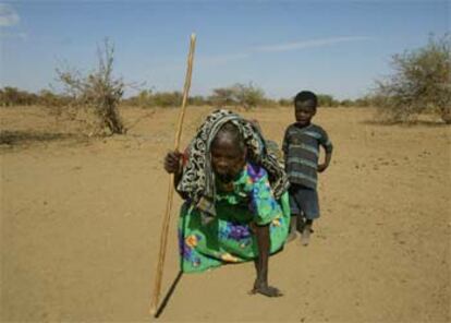 Una anciana sudanesa ciega intenta ponerse de pie ante la atenta mirada de su nieto en un campo de refugiados de Chad.