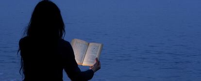 Una joven lee un libro en la playa