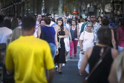 Una dona creua el carrer i mira el telèfon a la vegada.