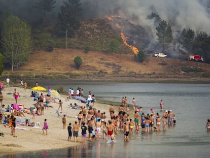 Bañistas en Ponte Sampaio contemplan desde la playa el fuego que arrasa el monte.