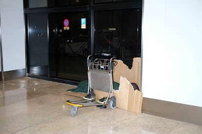 Una persona duerme en los pasillos que conectan la terminal 1 y 2 de Barajas durante la madrugada del lunes. 