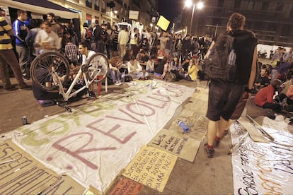 Ya terminada la manifestación, se producen disturbios en la zona de Centro. Además de a la quema de contenedores y destrozos en el mobiliario urbano, los enfrentamientos causan siete heridos, cinco de ellos, policías nacionales. Hay 24 detenidos. Tras los incidentes, varios participantes vuelven a la Puerta del Sol y celebran una asamblea. Deciden montar una acampada y pasar la noche en la plaza. Son unos 200. Votan a favor de que se quede la tienda de campaña, que la policía les ha pedido que retiren. Se organizan en comisiones: la de limpieza, para que Sol no se convierta en un vertedero; la de comunicación, para gestionar las redes sociales y homogeneizar su voz; la de extensión, para explicar a los curiosos de qué va esto; la de materiales, para seguir elaborando pancartas de protesta; la legal, para los pleitos que puedan surgir. La intendencia está resuelta: táperes llenos de croquetas, filetes rusos y tortilla, uvas, decenas de garrafas de agua, y pan, mucho pan que les han llevado voluntarios y aportaciones de pequeños comercios. La cuenta de correo abierta a las 13.00 tiene más de 500 mensajes electrónicos a las 16.00.