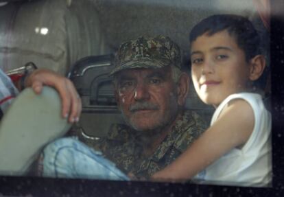 Un combatiende leal a Bachar el Asad junto a un niño, durante la evacuación de las aldeas de Fua y Kefraya.