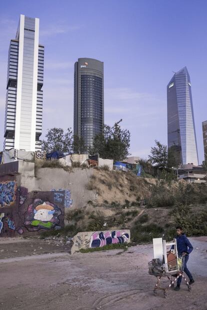 En la parte trasera del 'parking' de la estación madrileña de Chamartín hay un descampado con algunos edificios semiderruidos, pintados de grafitis, además de unas diez chabolas. Esta es una zona de obligatorio paso para los que vayan andando desde la estación hasta la Castellana. Al fondo, las Cuatro Torres, el centro financiero más importante de la ciudad.