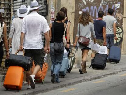 Unos turistas arrastran sus maletas, camino del hotel, en el centro de Valencia