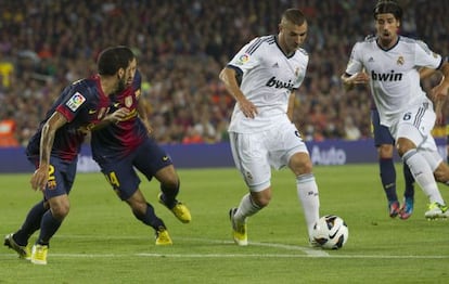 Benzema intenta superar a Mascherano y a Alves.