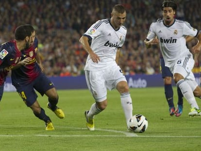 Benzema intenta superar a Mascherano y a Alves.