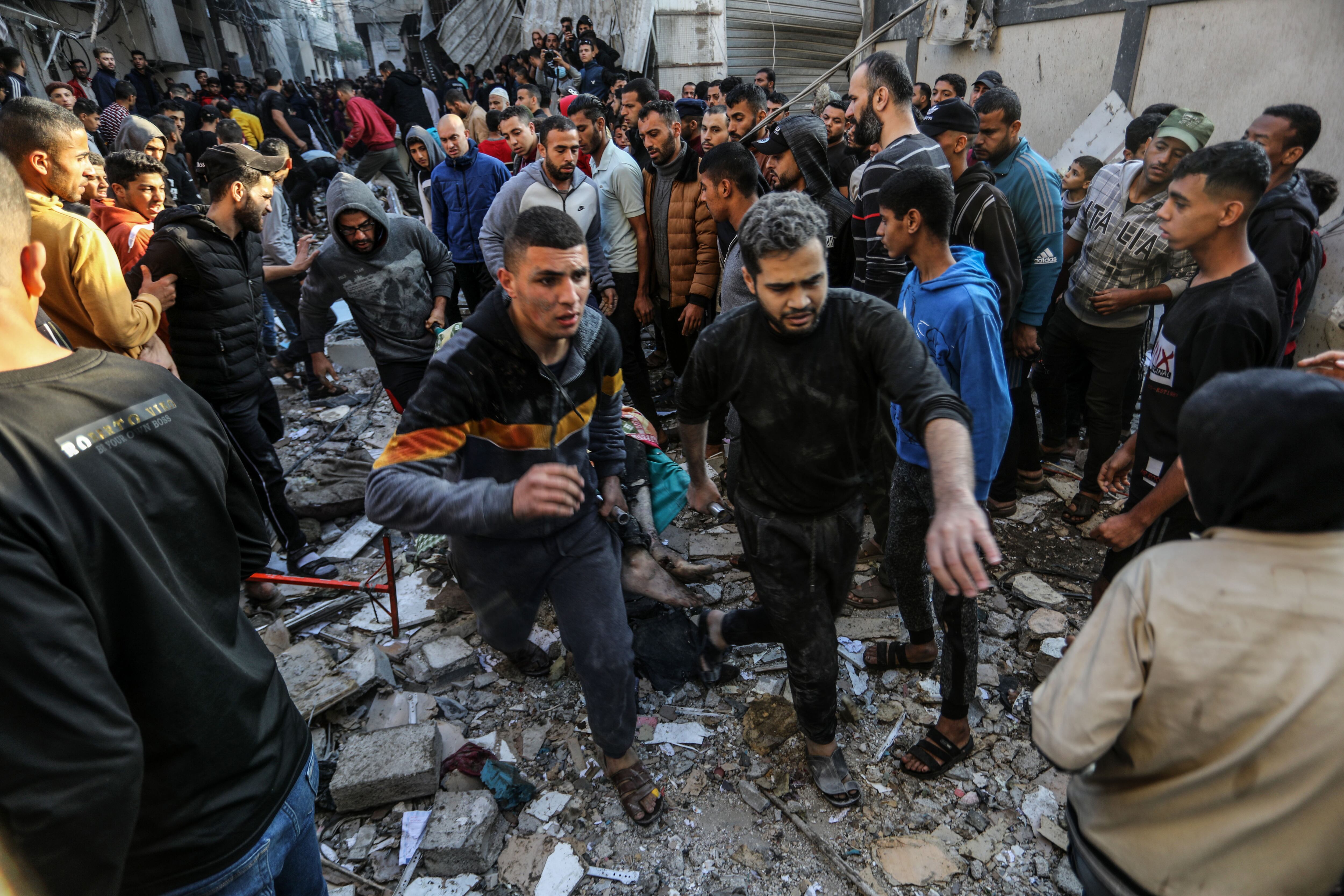 Hombres palestinos transportan el cuerpo de una víctima, tras un ataque aéreo israelí que ha afectado a la casa de la familia Adwan, este viernes en Rafah.