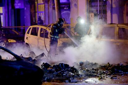 Bombers apaguen un dels deu cotxes incendiats durant les protestes independentistes. 