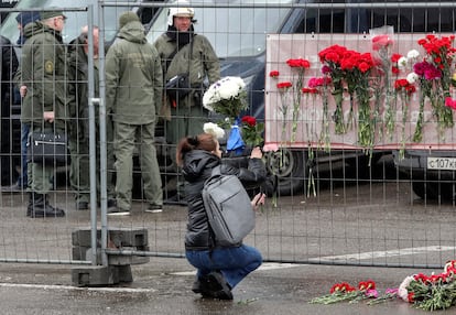 Una mujer colocaba flores este sábado en una valla en el exterior de la sala de conciertos Crocus. 