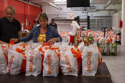 Un grupo de voluntarios preparan bolsas con alimentos en Carouge, Suiza.