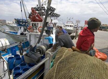 Pescadores de Isla Cristina realizan labores de mantenimiento en los barcos amarrados.