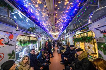 Los pasajeros del metro de Moscú se sientan dentro de un vagón con decoración navideña. 
