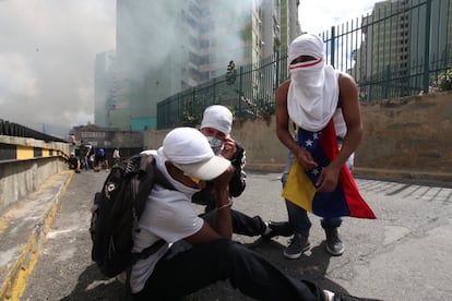 Opositores movilizados en el Este de Caracas se protegen de los gases. 