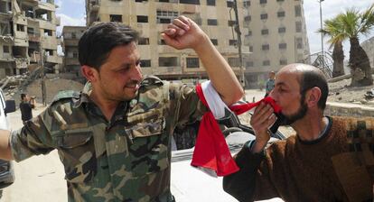 Un hombre besa la bandera siria después de que soldados del régimen de El Asad entraran en Duma el 14 de abril de 2018.