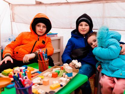 Iliusha (11 años, a la izquierda), Misha (10, en el centro) y Dasha (4, a la derecha) Shum, hermanos de Odesa, juegan en un Punto Azul de Unicef, en el paso fronterizo de Palanca, Moldavia.