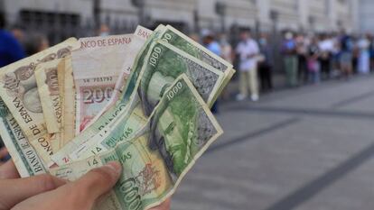 Una persona muestra varios billetes de las antiguas pesetas, mientras espera cola en junio de 2021 a las puertas del Banco de España para canjearlas.