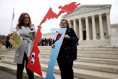 Dos personas con el trazado de mapas electorales protestan el miércoles frente al Tribunal Supremo, en Washington