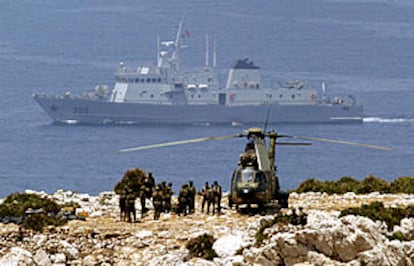 Legionarios españoles se disponen a abandonar el islote de Perejil, frente al que patrulla  un barco de guerra.