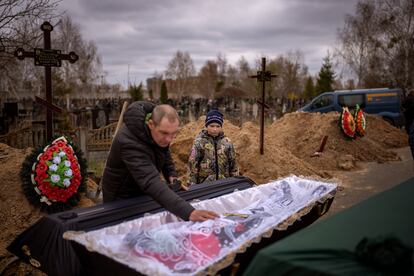 Vova, de 10 años, mira el cuerpo de su madre, Maryna, que yace en un ataúd mientras su padre, Ivan Drahun, reza durante su funeral en Bucha, en las afueras de Kiev. La madre de Vova murió mientras se refugiaba en un sótano frío durante más de un mes en el que las tropas rusas se adueñaron de la ciudad.  