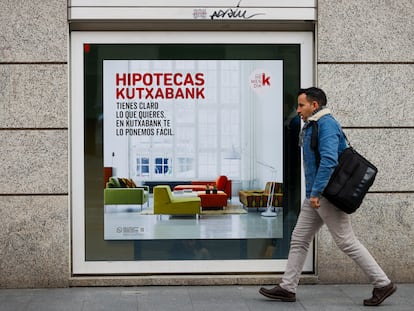Un hombre pasa frente a un banco con publicidad de hipotecas.