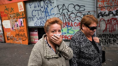 Mujeres caminan frente a una tienda pintada por manifestantes antigubernamentales en Santiago, Chile, en 2019.