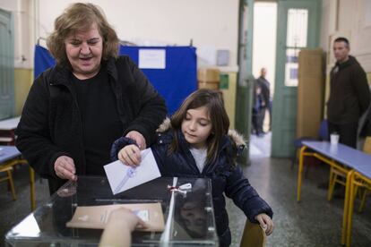 Una dona amb una nena diposita el seu vot a Atenes.