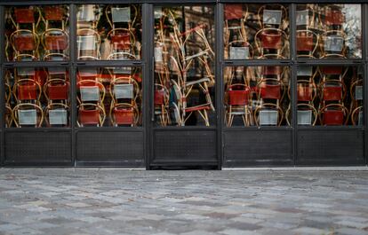 Sillas apiladas tras las puertas de un restaurante cerrado en París a causa de la epidemia de coronavirus